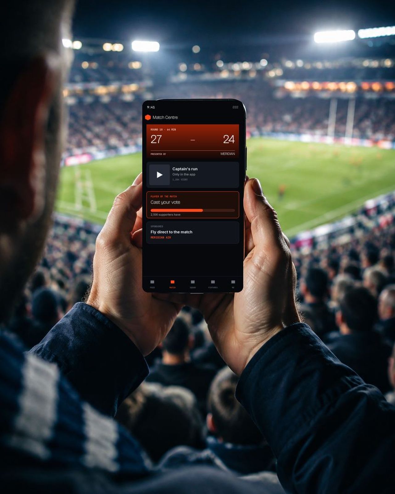 A supporter in a stadium holding a phone showing a live match centre